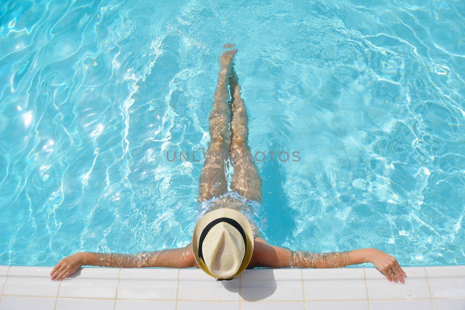 Happy smiling woman with hat and sunglasses  in swimming pool at tropical resort