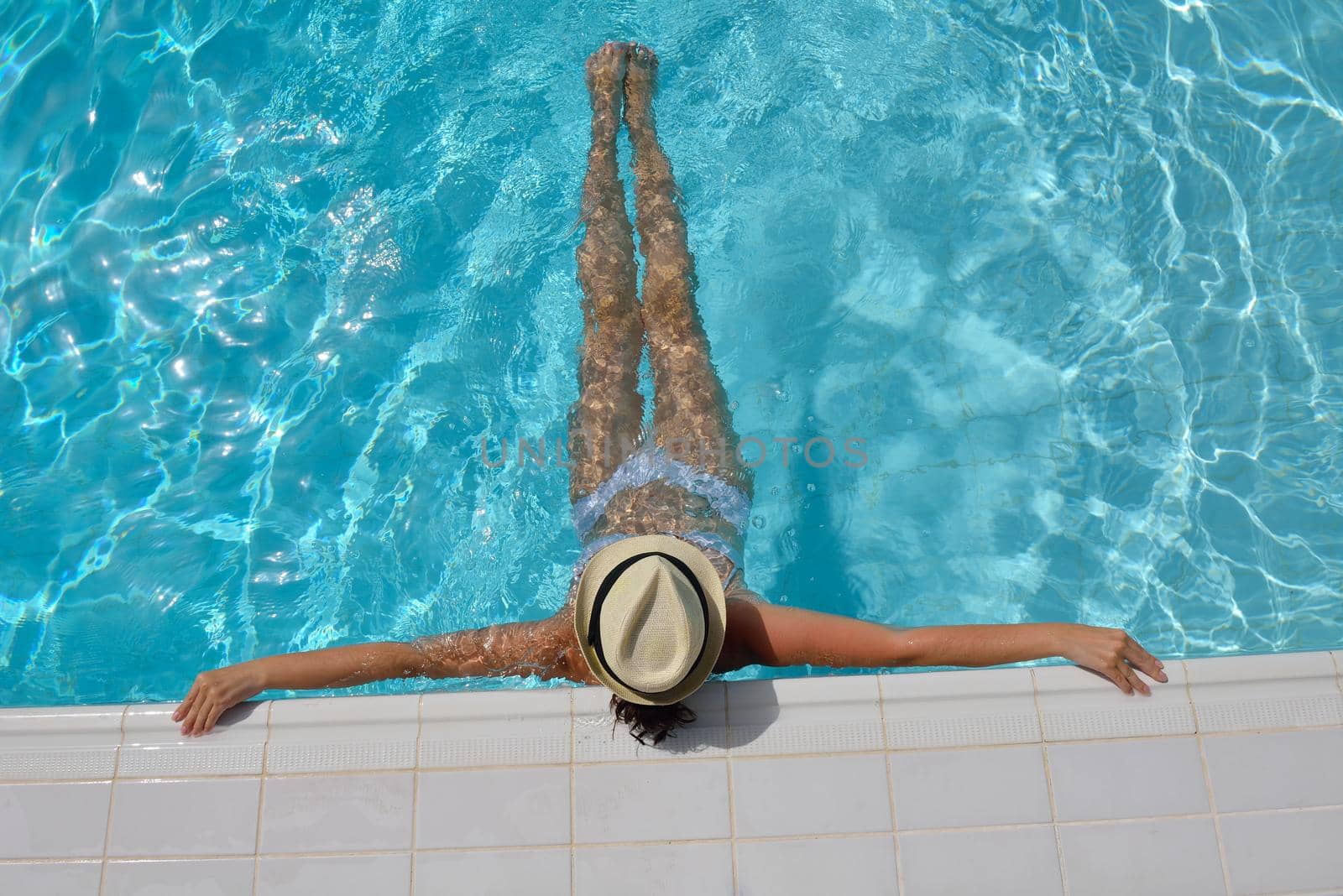 Happy smiling woman with hat and sunglasses  in swimming pool at tropical resort