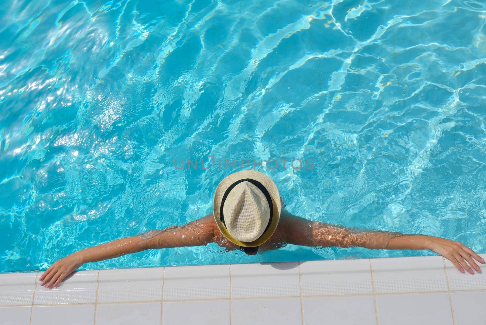 Happy smiling woman with hat and sunglasses  in swimming pool at tropical resort