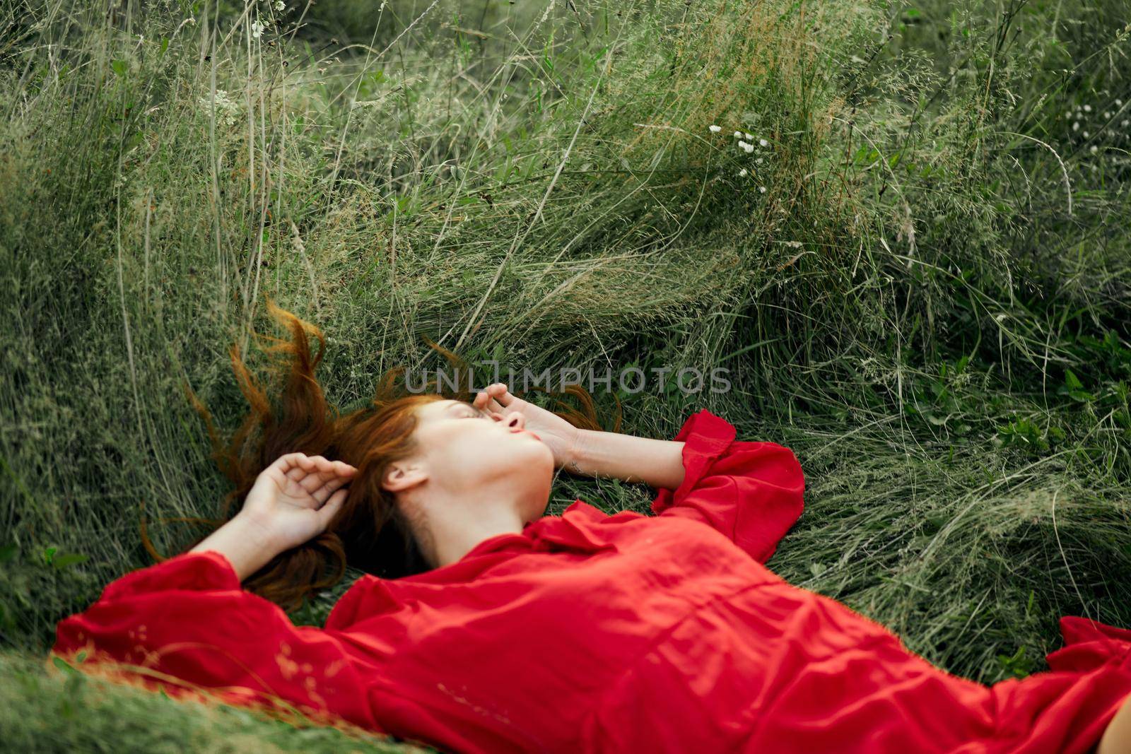 woman in red dress lies on the grass charm freedom. High quality photo