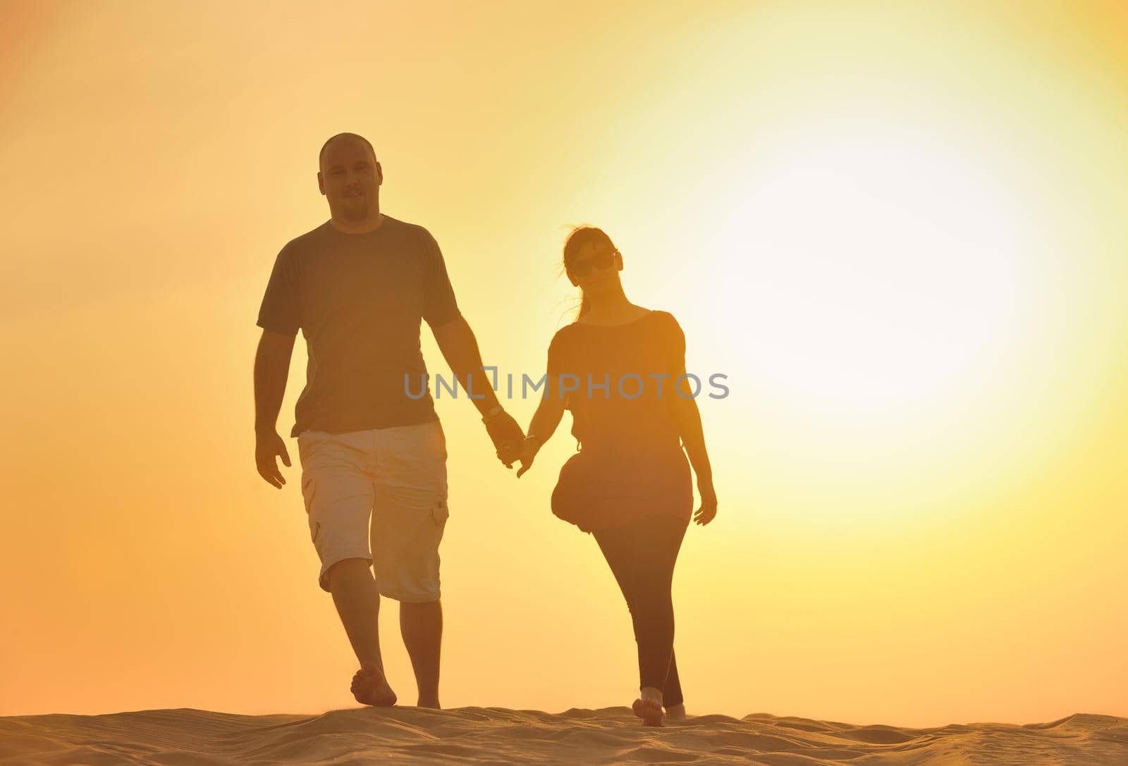 relaxed young pasionate couple enjoying the sunset  beauty on their honeymoon, on a desert with orange background