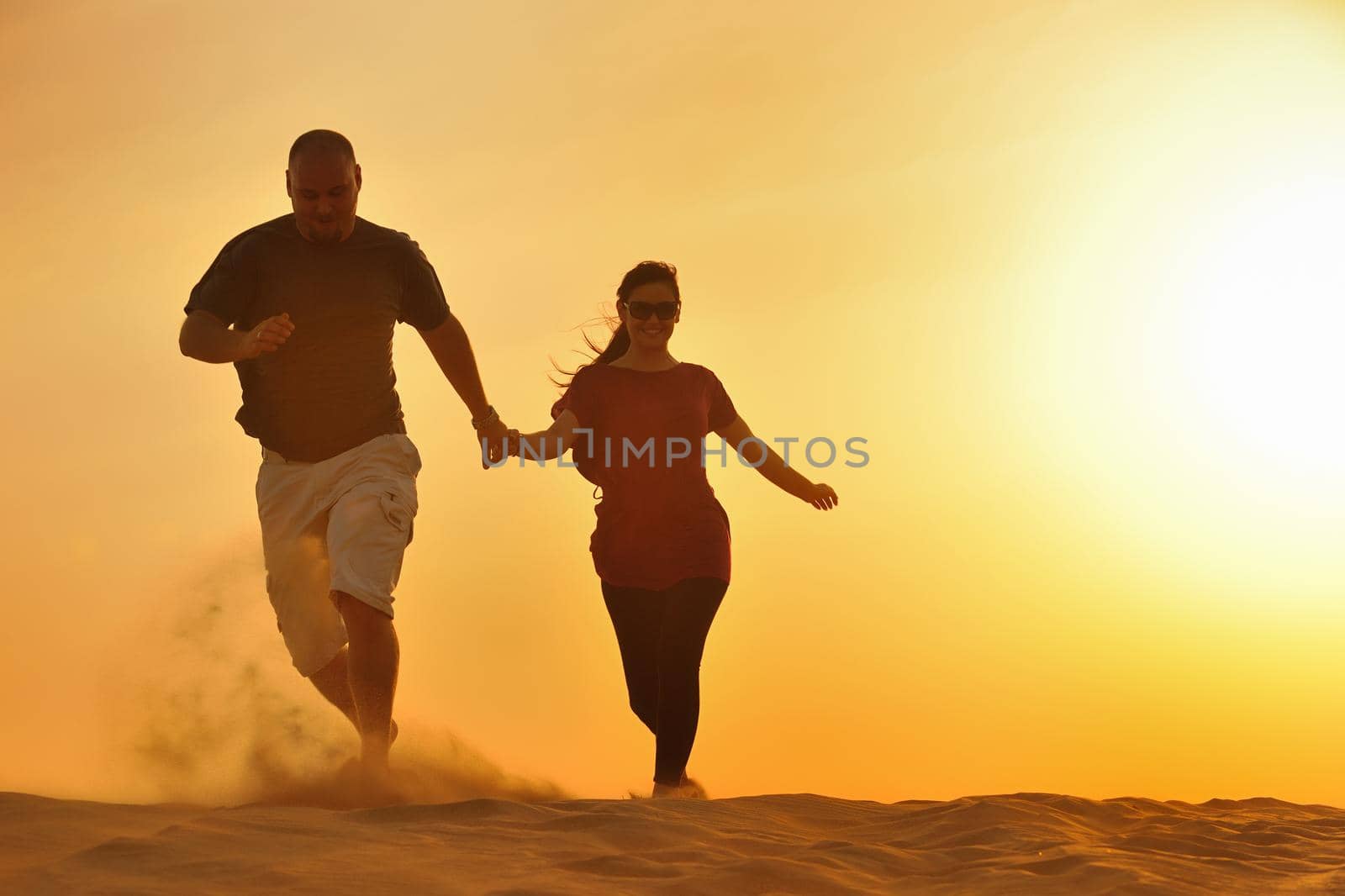 relaxed young pasionate couple enjoying the sunset  beauty on their honeymoon, on a desert with orange background