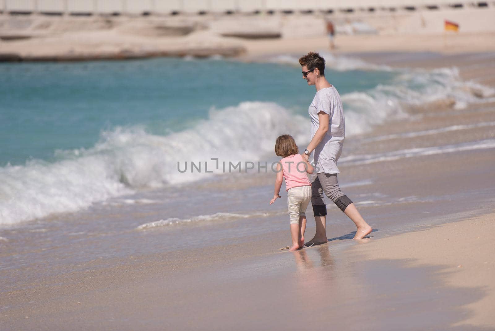 beautiful young mother and cute little girl are enjoying while running on exotic beach along the ocean Travel and Vacations.