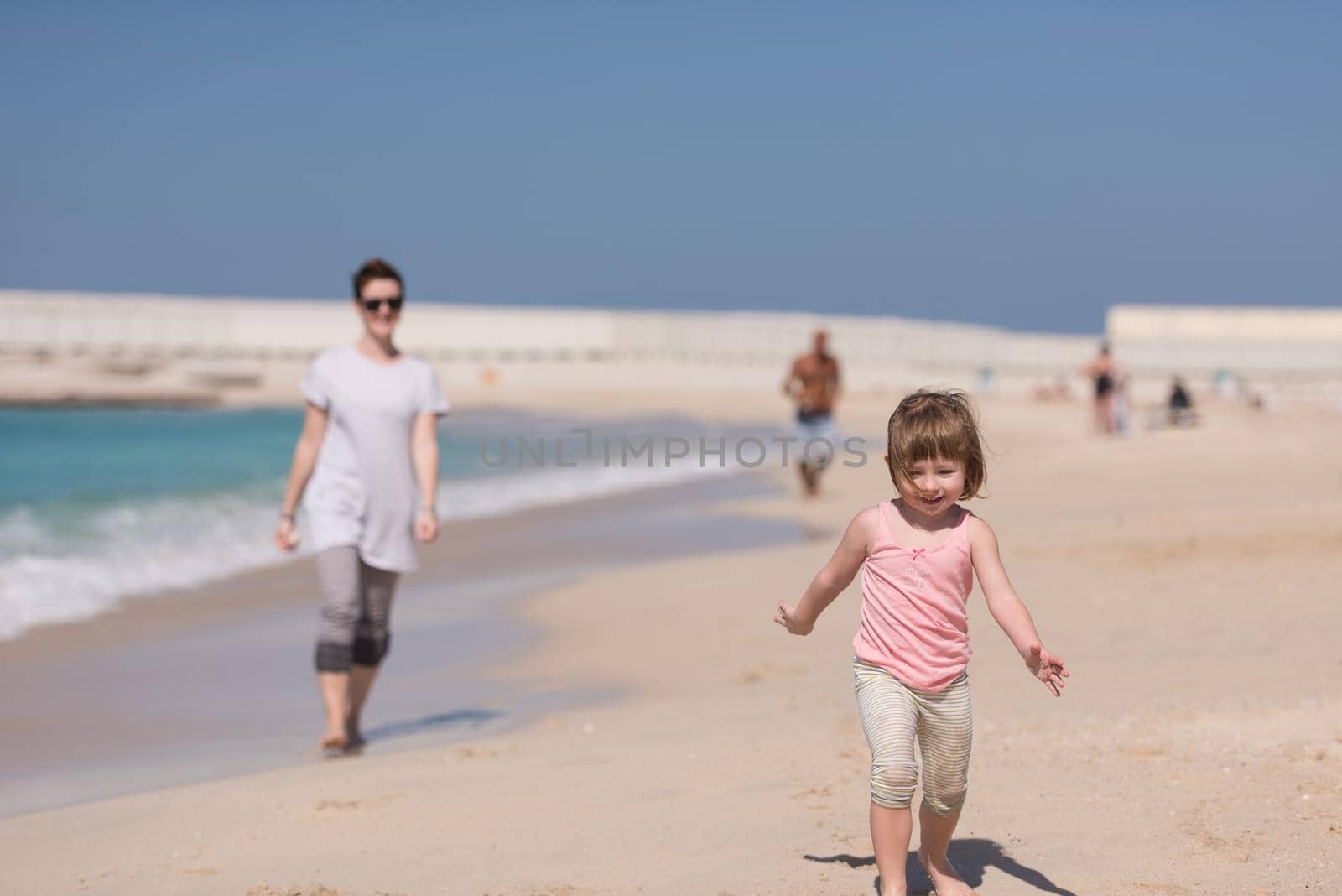 beautiful young mother and cute little girl are enjoying while running on exotic beach along the ocean Travel and Vacations.