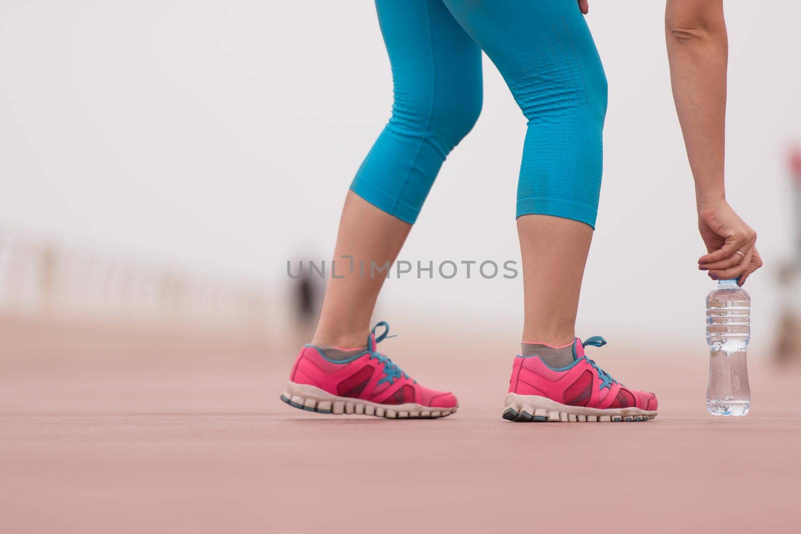 Fitness woman training and jogging in summer park, close up on running shoes and bottle of water. Healthy lifestyle and sport concept
