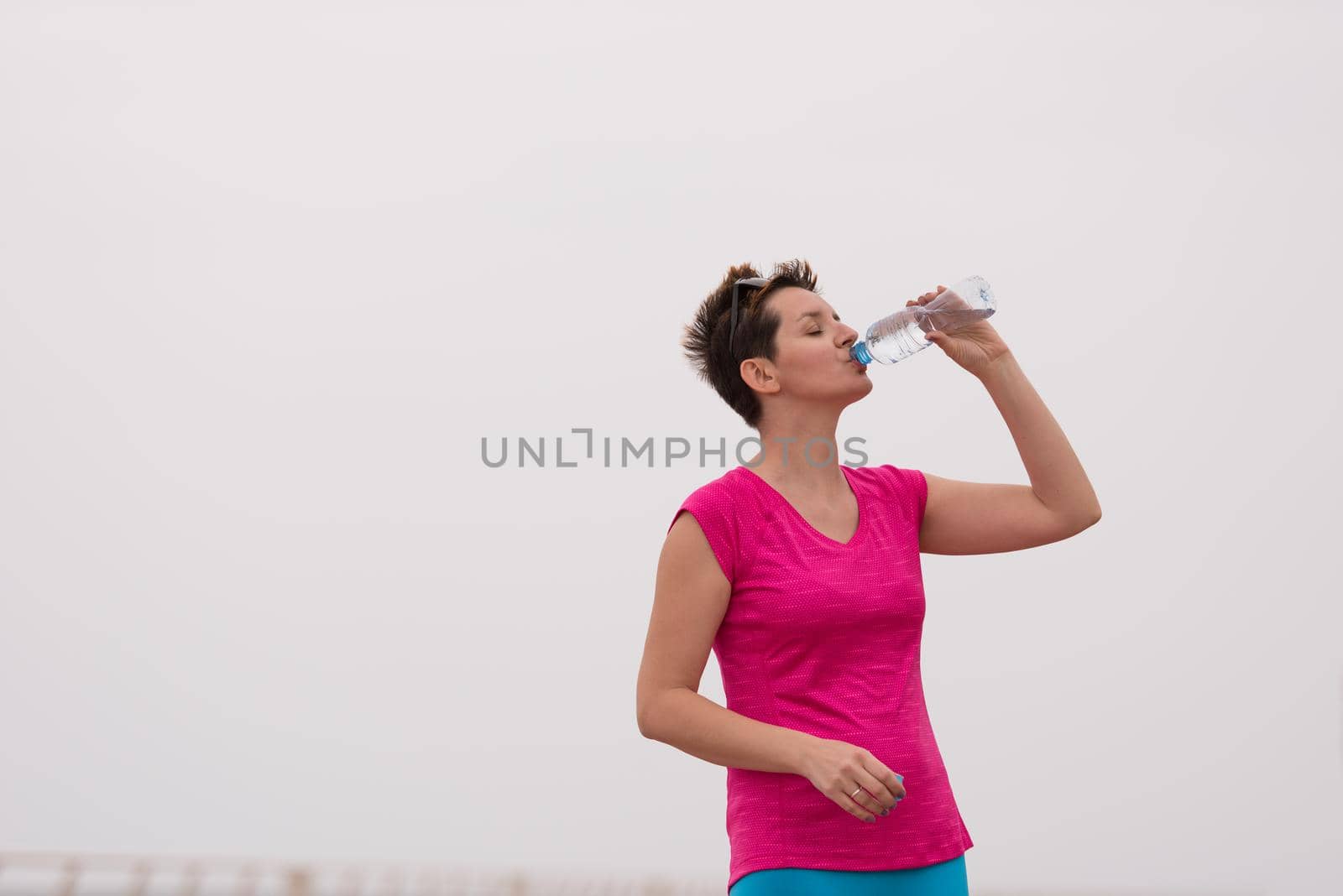 Fitness woman drinking water by dotshock