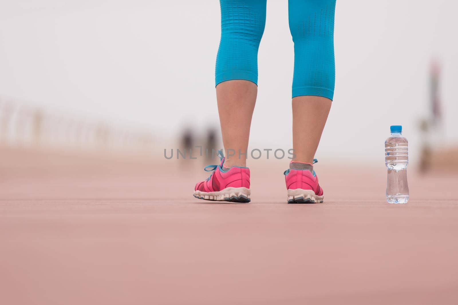 Fitness woman training and jogging in summer park, close up on running shoes and bottle of water. Healthy lifestyle and sport concept