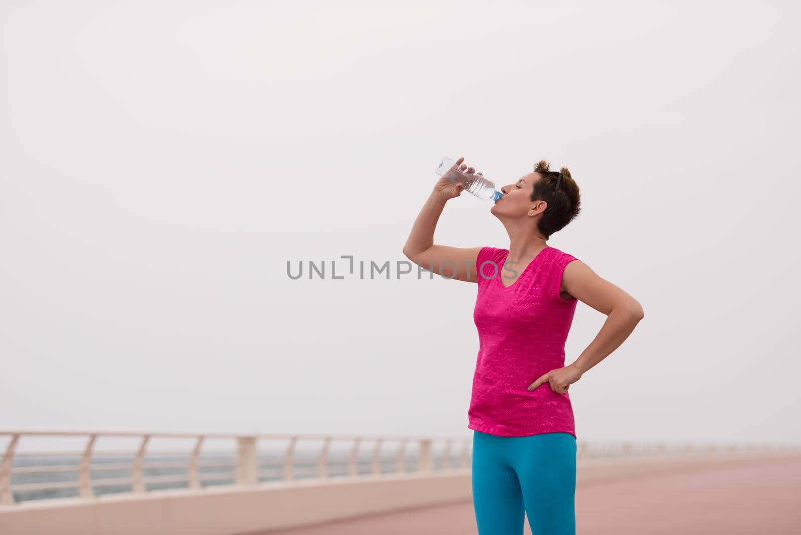 Fitness woman drinking water by dotshock