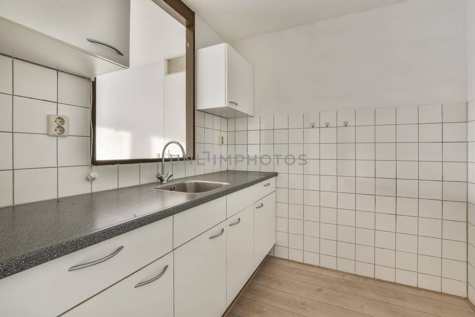 A well-organized interior of a small home kitchen with a sink under the window and light furniture in a city apartment