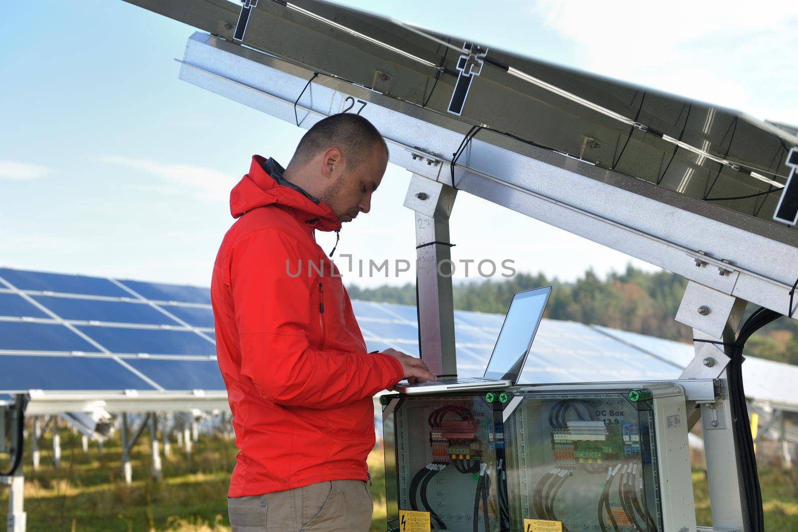 engineer using laptop at solar panels plant field by dotshock