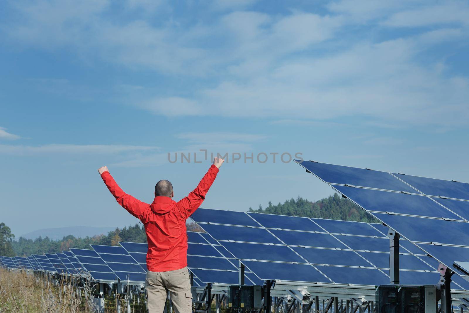 Male engineer at work place, solar panels plant industy in background