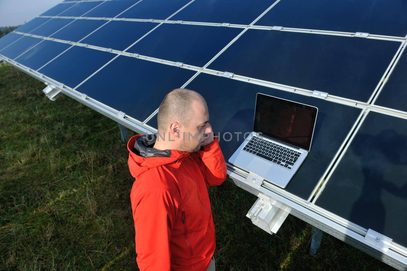 engineer using laptop at solar panels plant field by dotshock