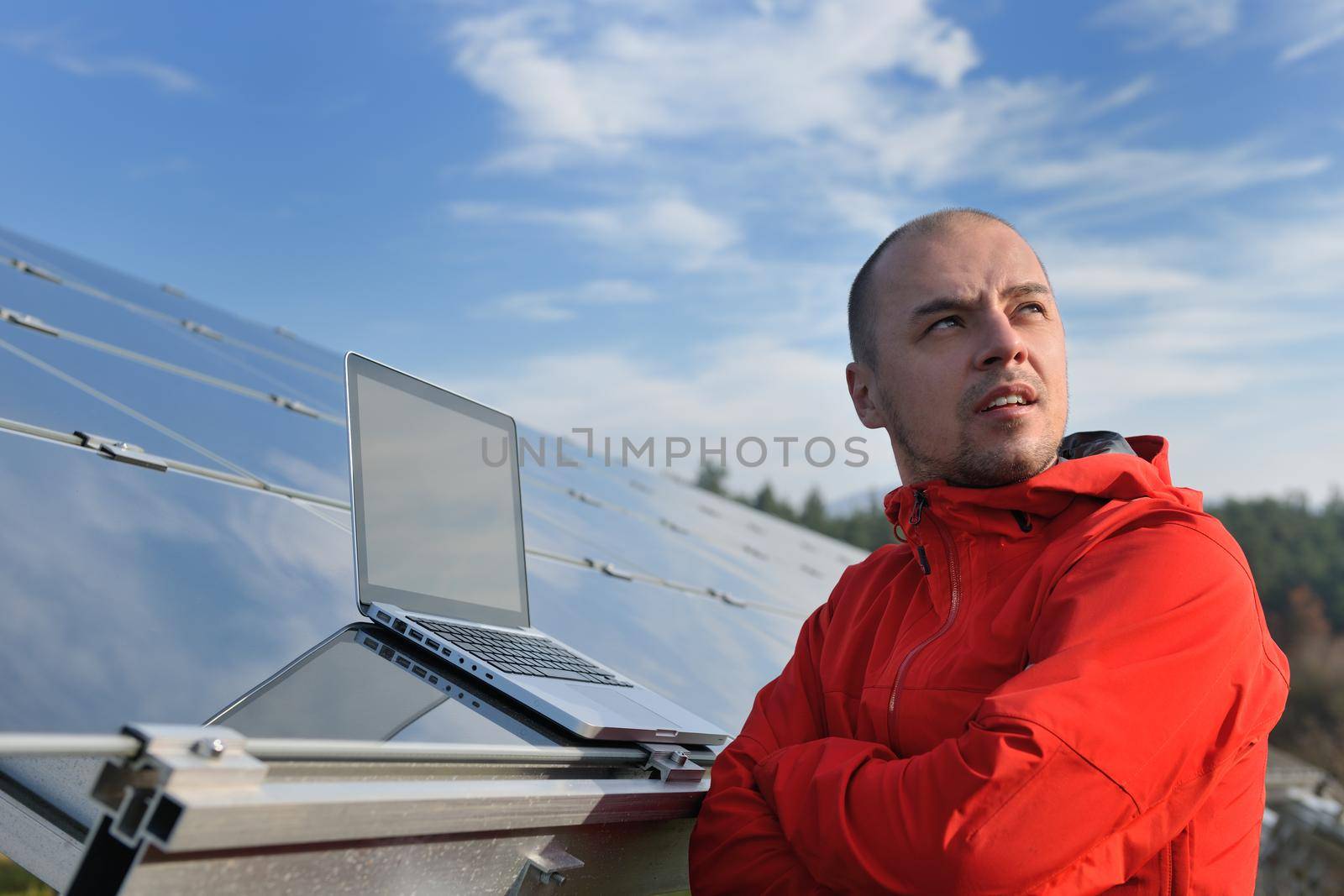 engineer using laptop at solar panels plant field by dotshock
