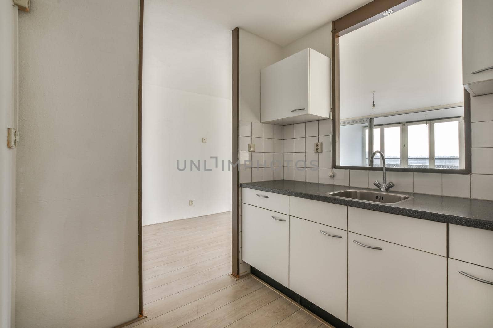 A well-organized interior of a small home kitchen with a sink under the window and light furniture in a city apartment