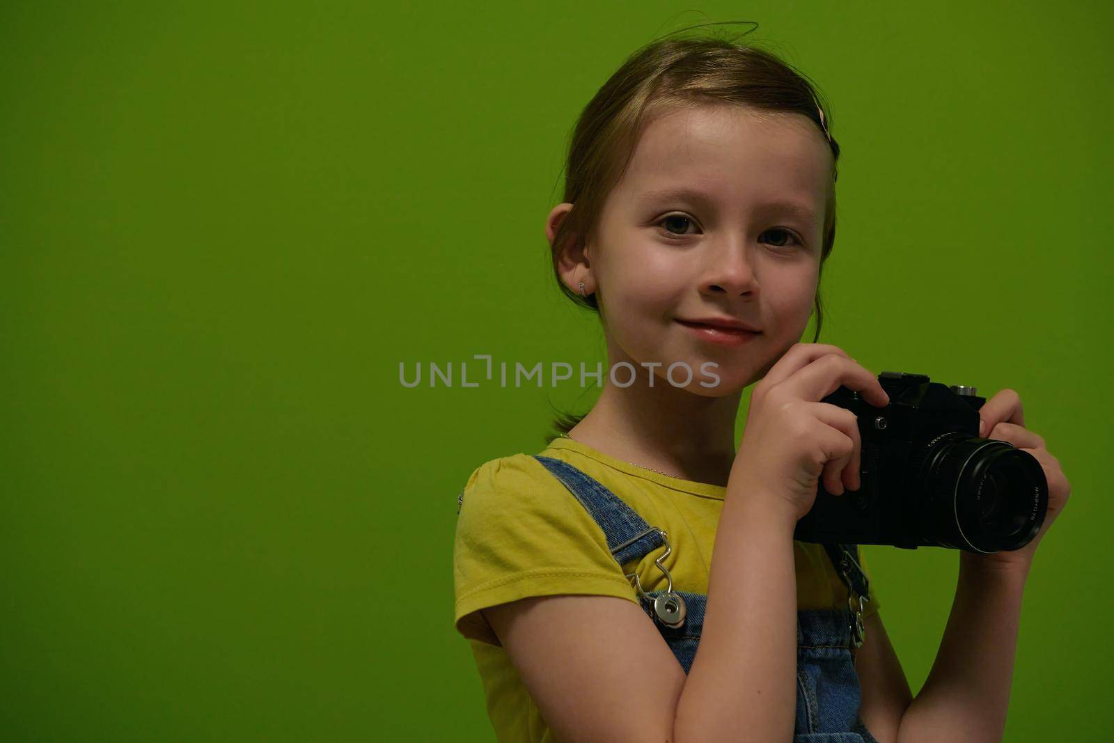 Cute little girl taking picture using vintage old retro film photo camera