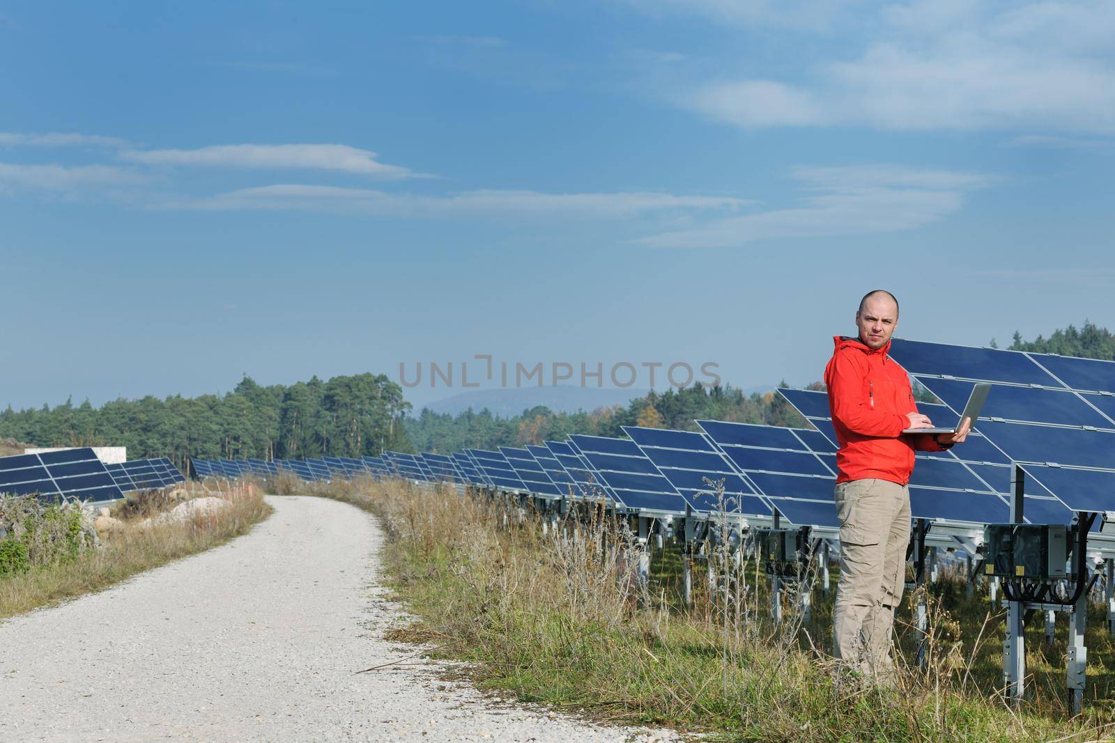 business man  engineer using laptop at solar panels plant eco energy field  in background