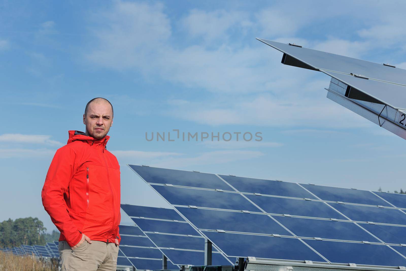 Male engineer at work place, solar panels plant industy in background