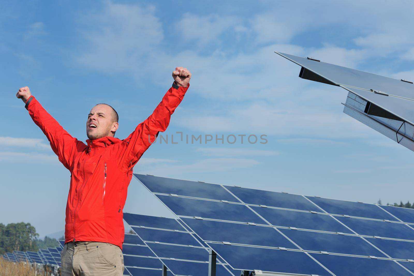 Male engineer at work place, solar panels plant industy in background