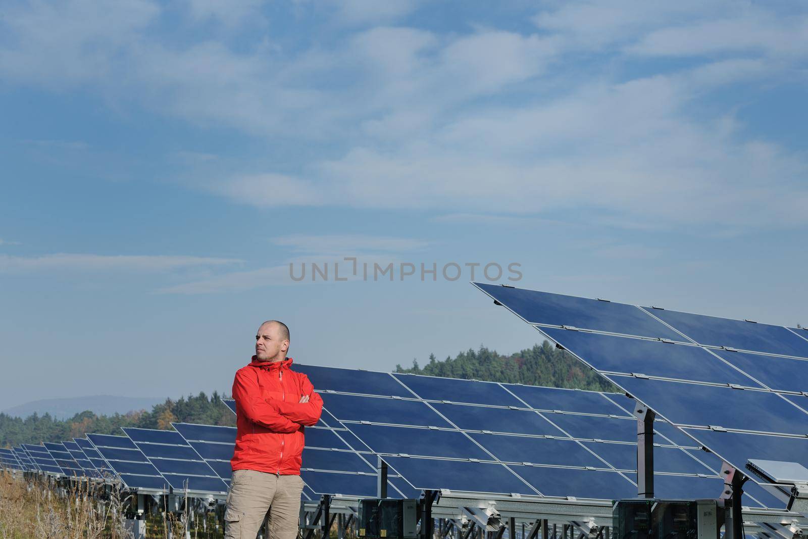 Male engineer at work place, solar panels plant industy in background