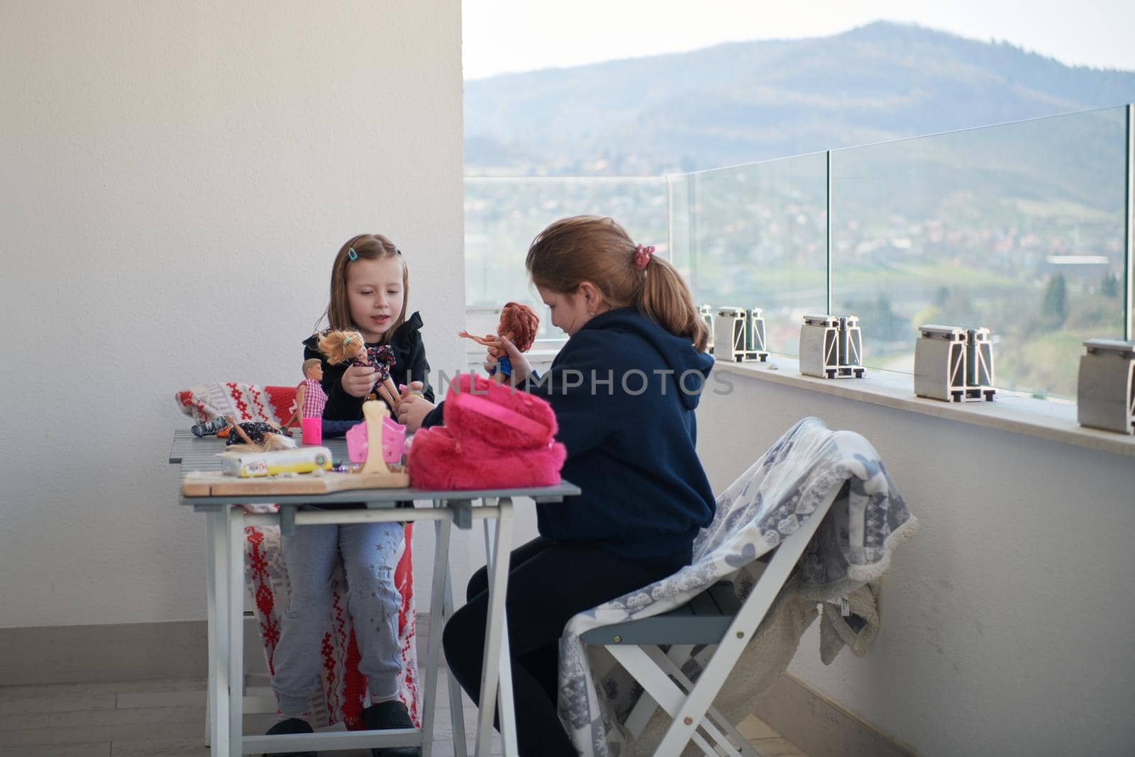 sisters or friends little girls playing with dolls on balcony