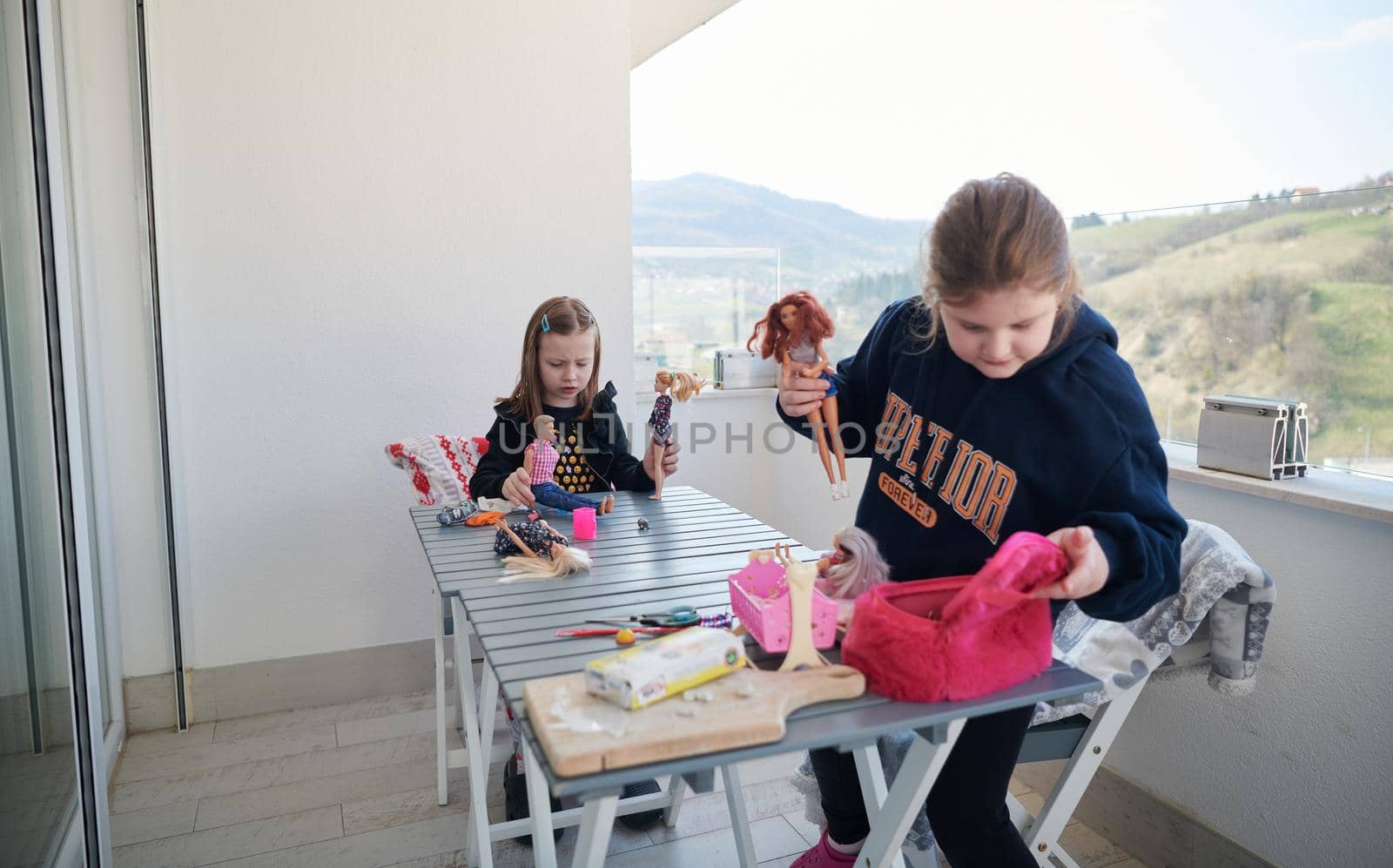 sisters or friends little girls playing with dolls on balcony