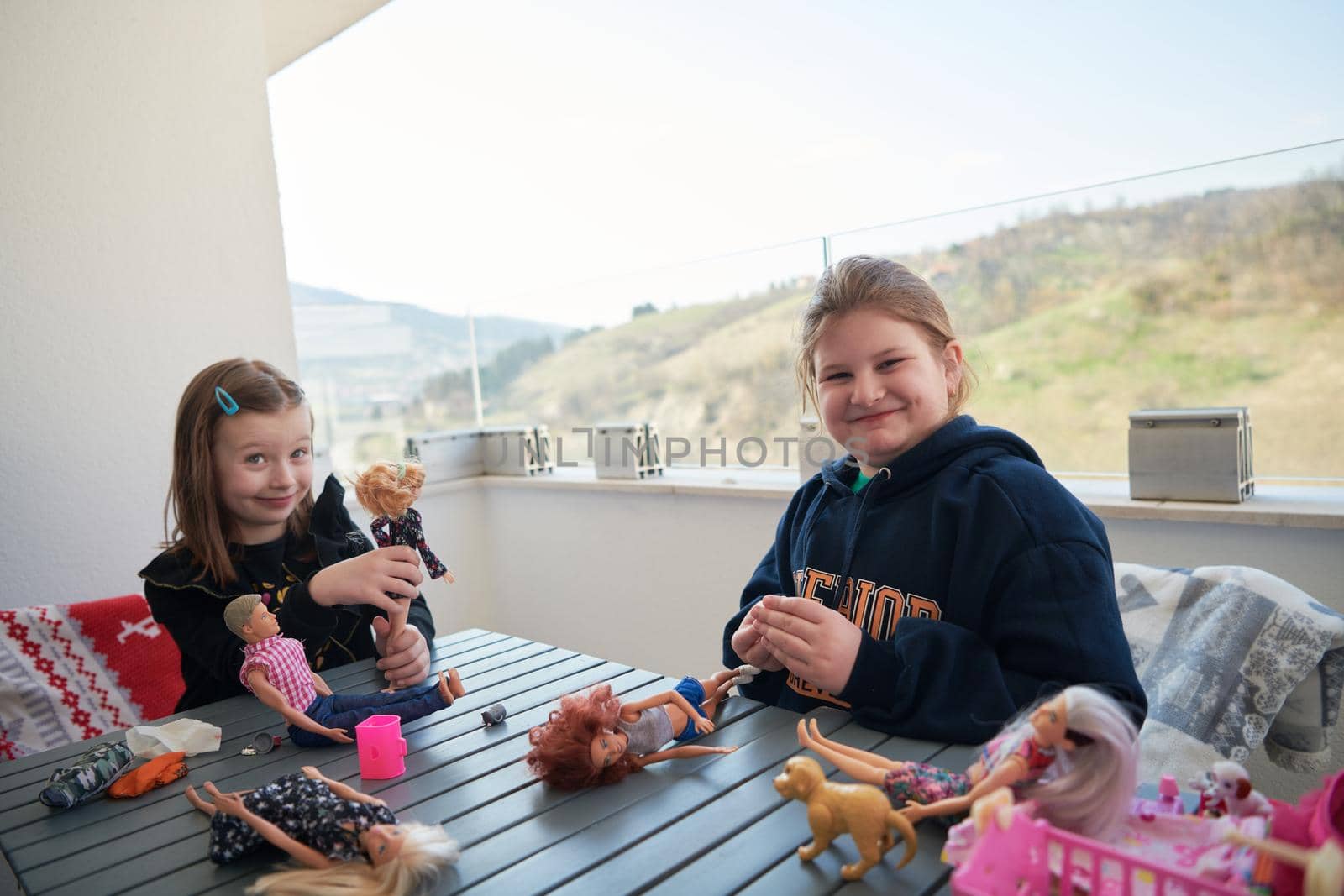 sisters or friends little girls playing with dolls on balcony