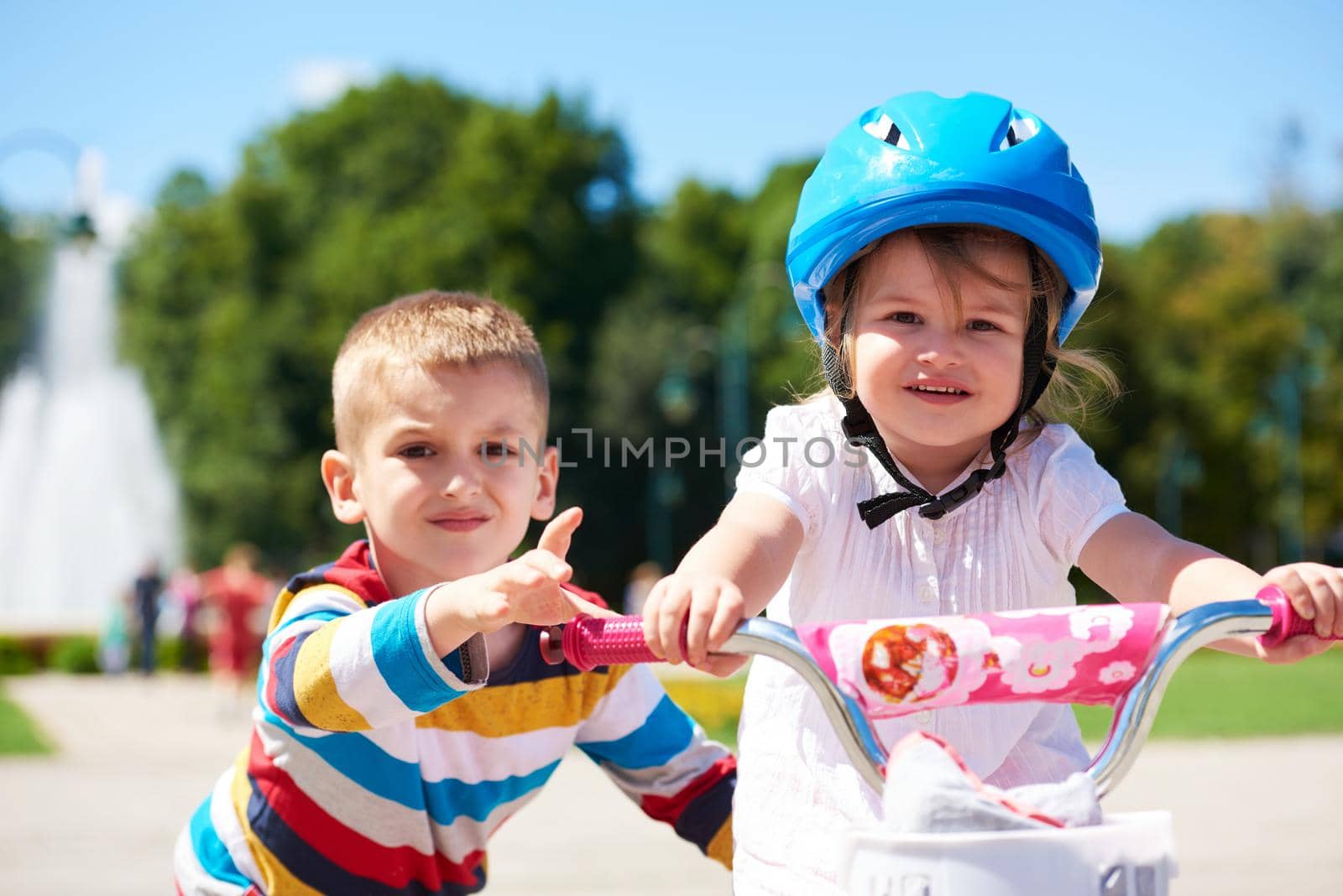 Boy and girl in park learning to ride a bike by dotshock