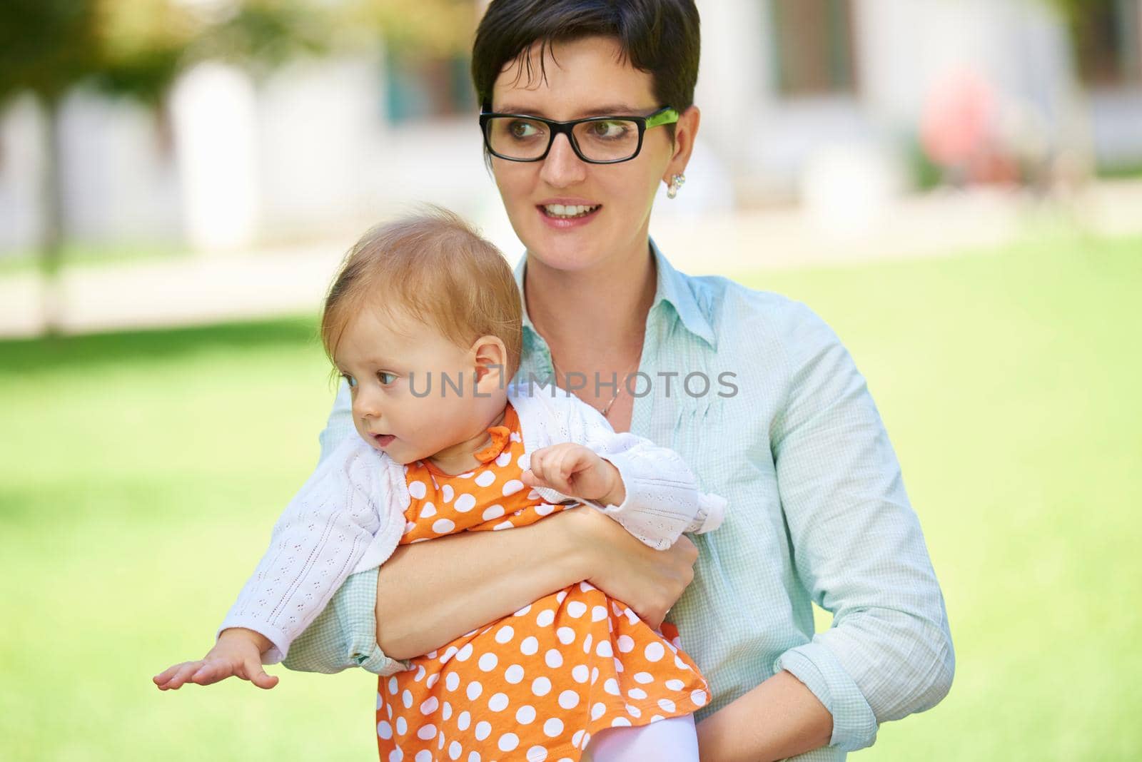 portrait of happy mom and baby daughter smiling at park nature