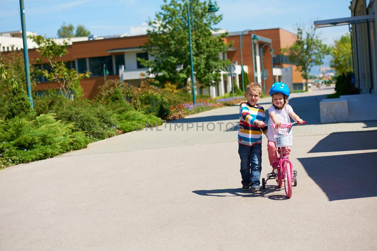 Boy and girl in park learning to ride a bike by dotshock