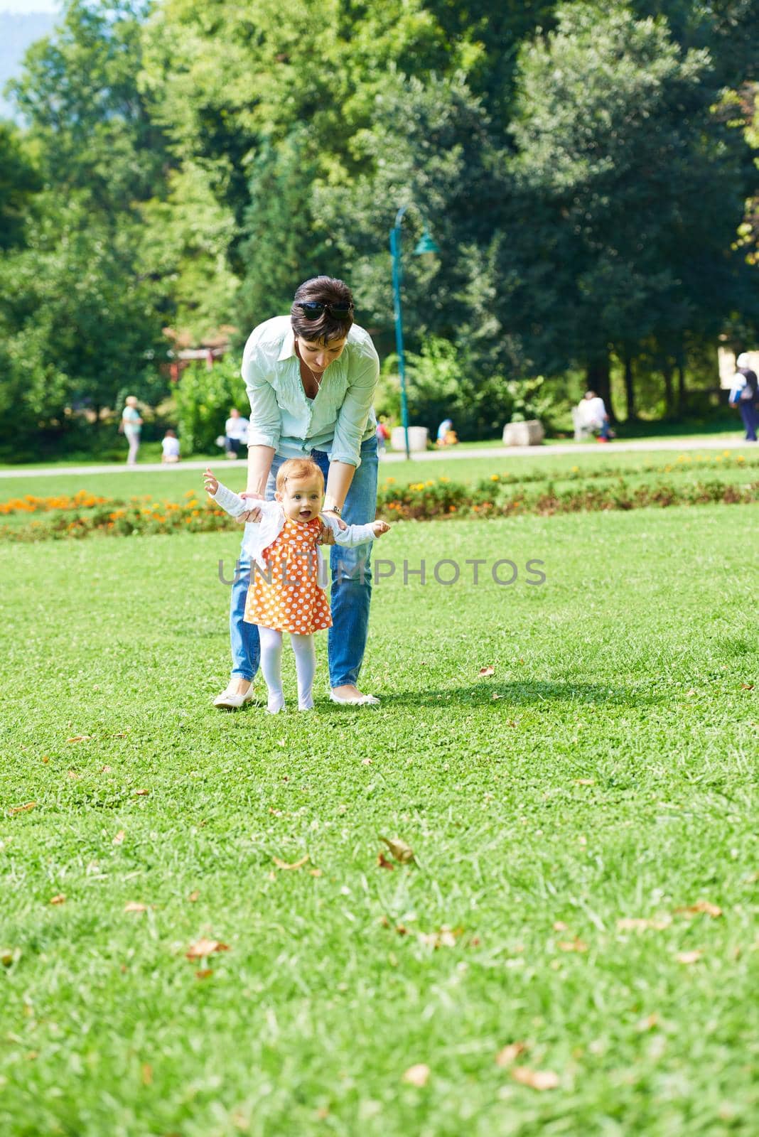 happy mother and baby child in park making first steps .  Walking and hugging.