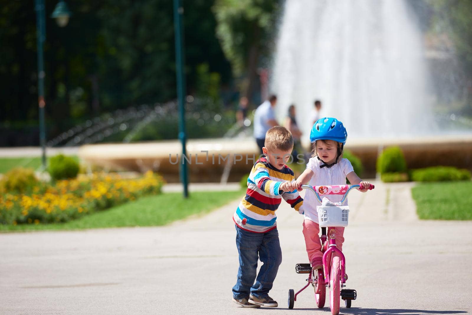 Boy and girl in park learning to ride a bike by dotshock