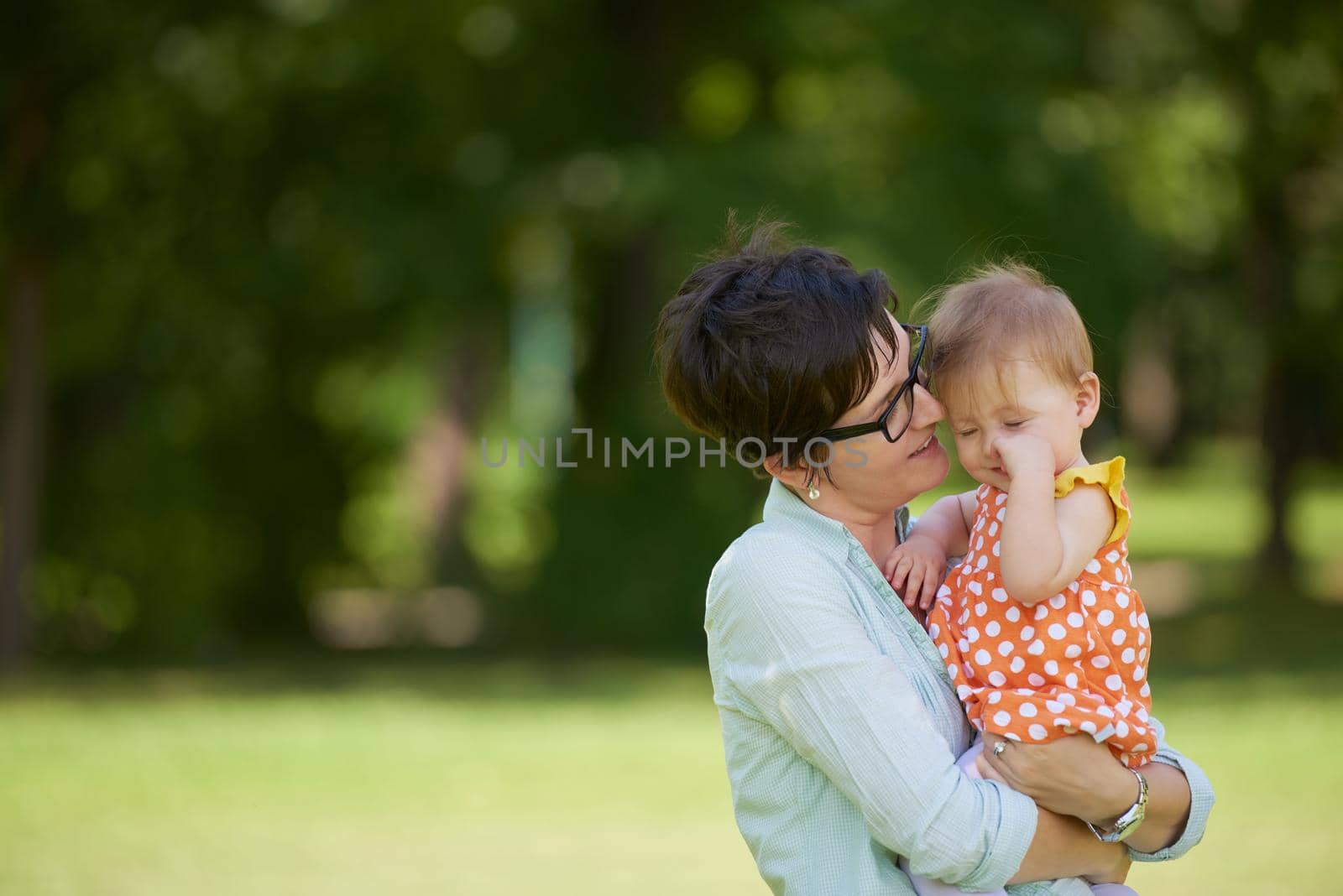 happy mother and baby child in park making first steps .  Walking and hugging.