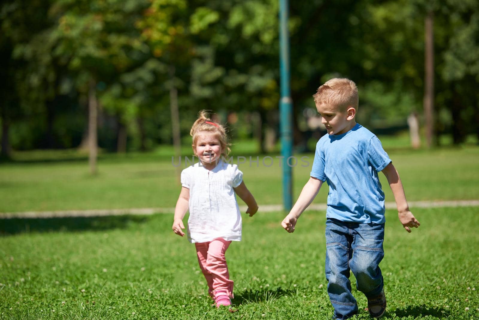 Boy and girl have fun and running. Happy child in park