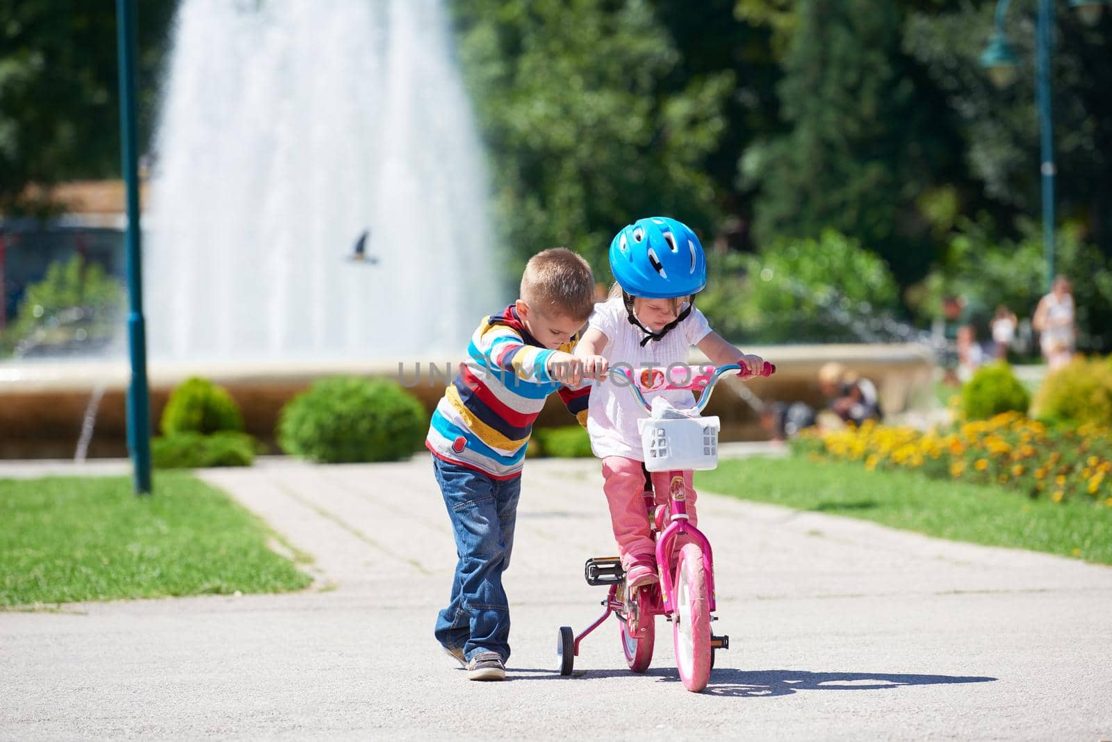 Happy childrens outdoor,  brother and sister in park have fun. Boy and girl in park learning to ride a bike.