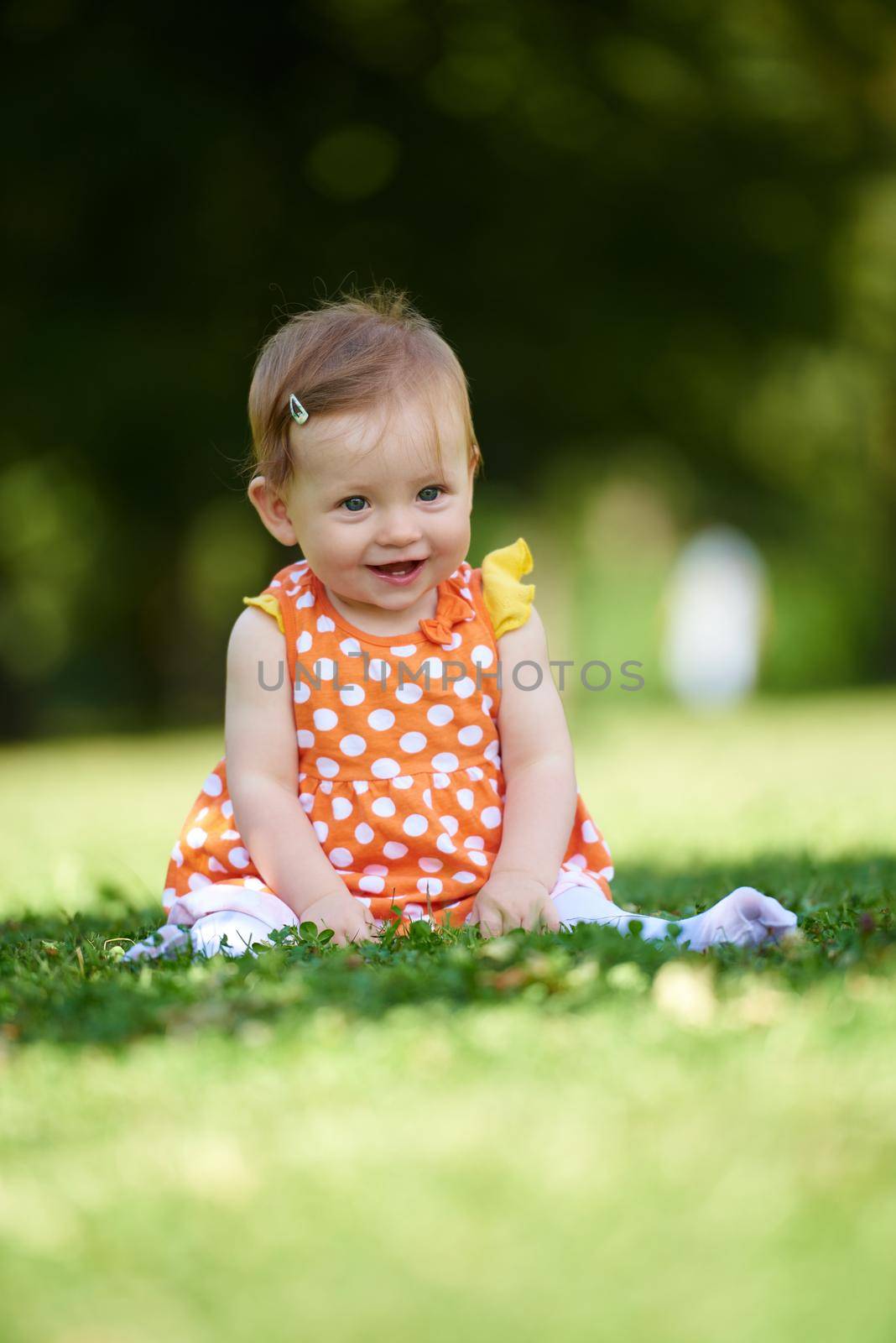 happy young baby child sittng on grass on beautiful summer day in park