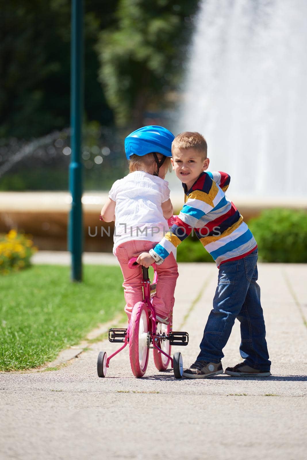 Boy and girl in park learning to ride a bike by dotshock