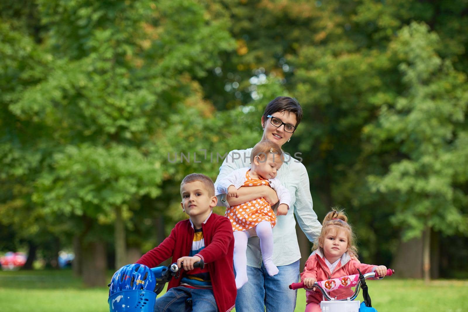 portrait of happy young family,  mother and  kids have fun in park