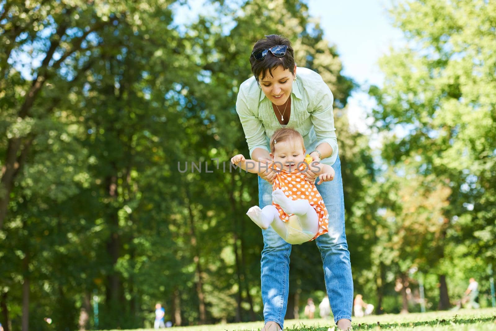 happy mother and baby child in park making first steps .  Walking and hugging.