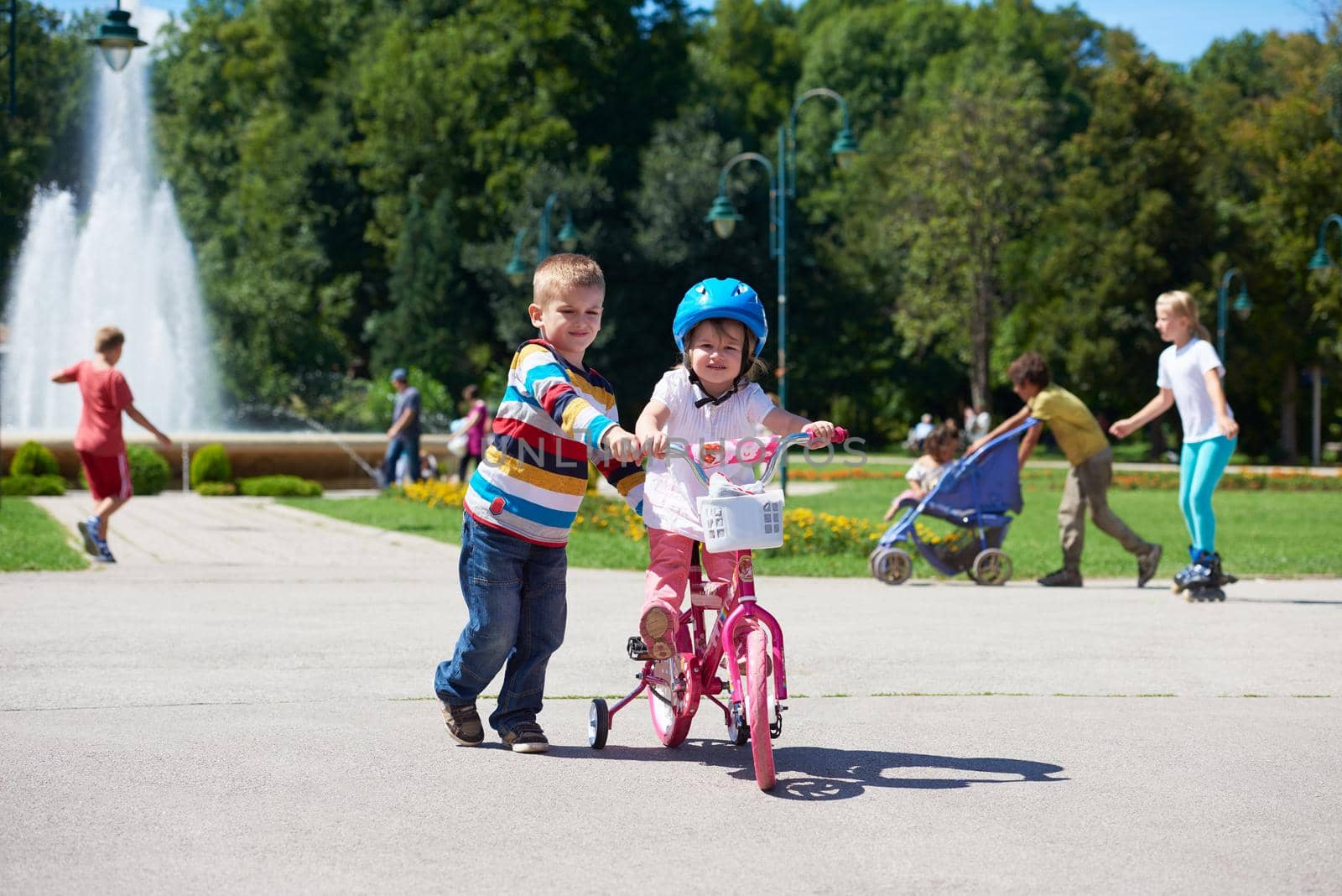 Happy childrens outdoor,  brother and sister in park have fun. Boy and girl in park learning to ride a bike.
