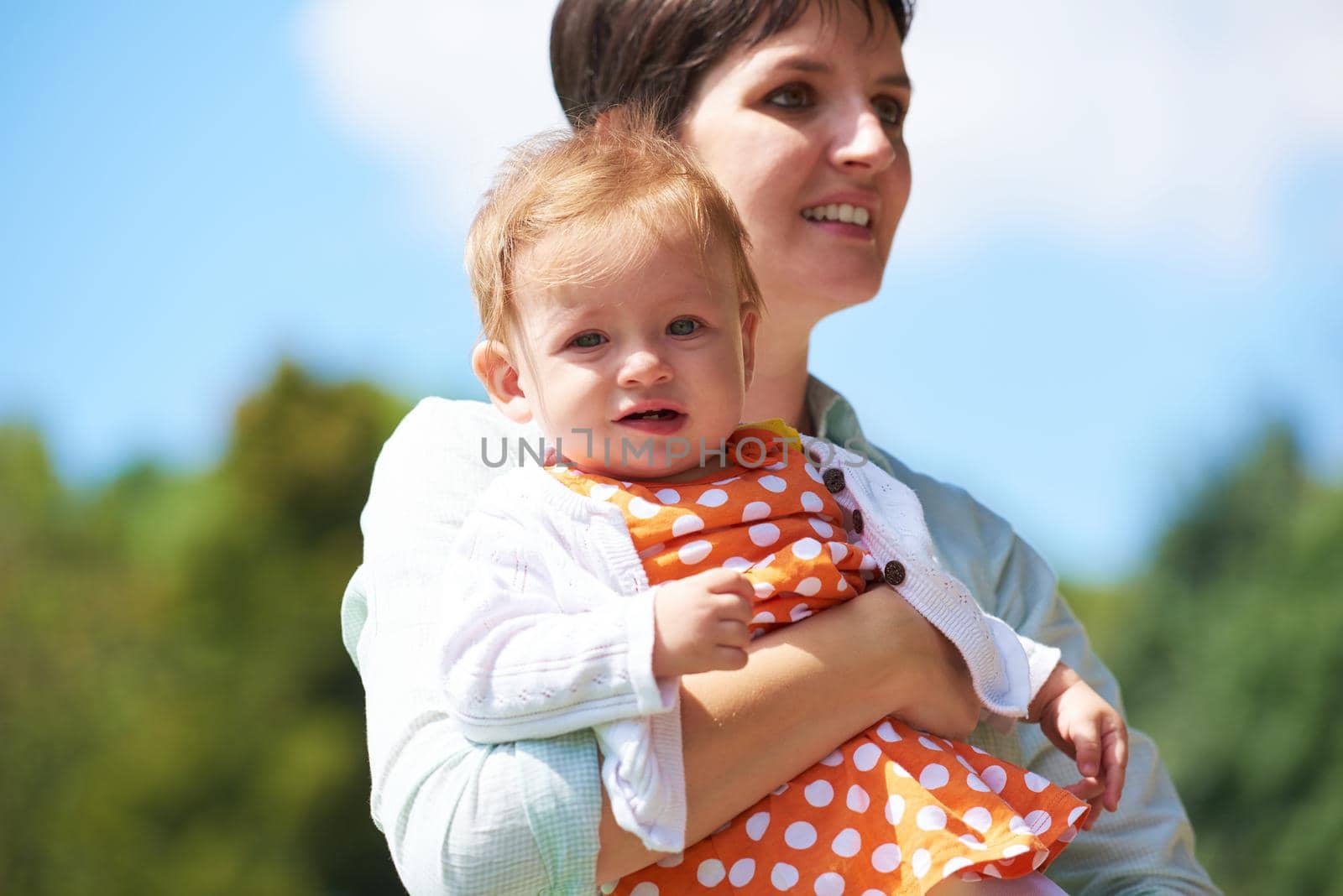 happy mother and baby child in park making first steps .  Walking and hugging.