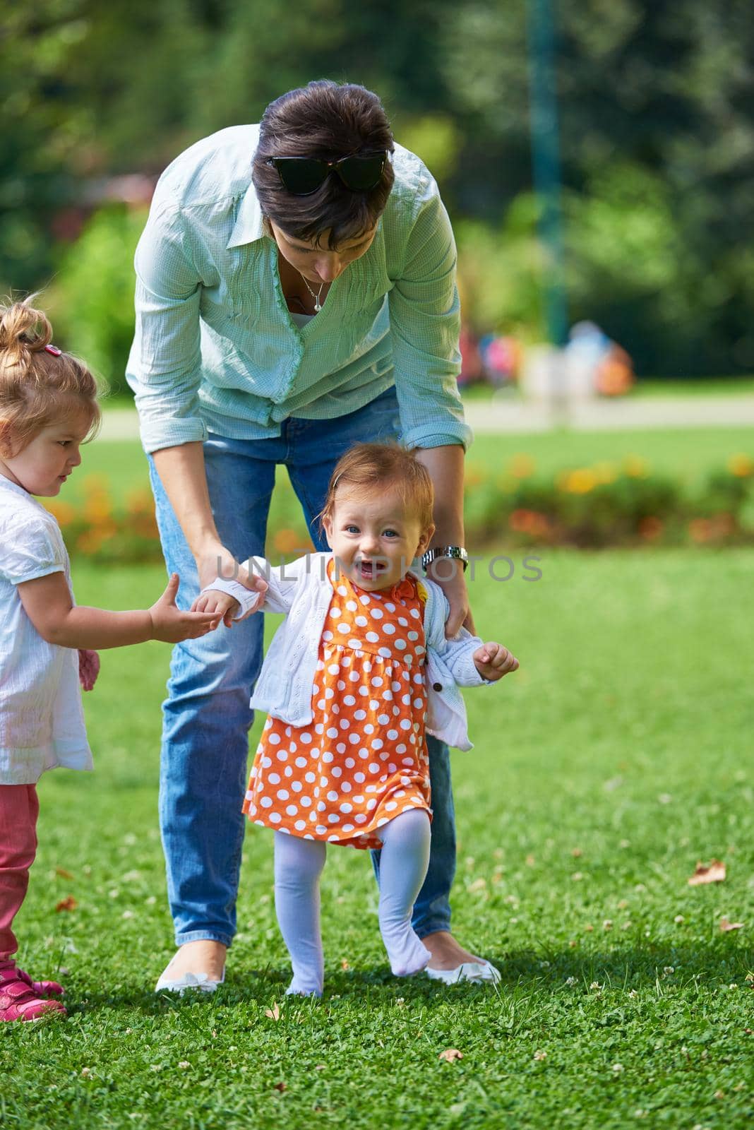 happy mother and baby child in park making first steps .  Walking and hugging.