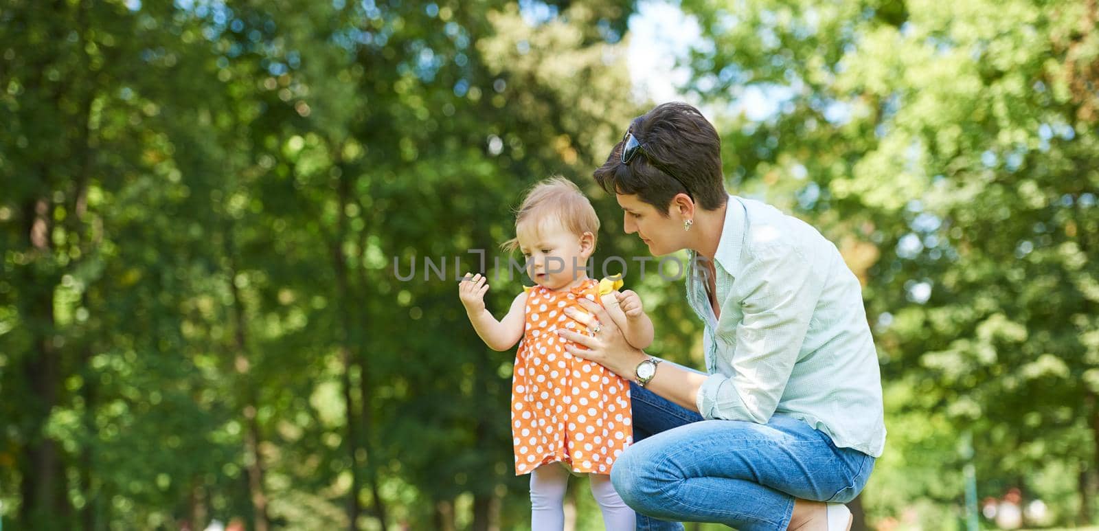 happy mother and baby child in park making first steps .  Walking and hugging.