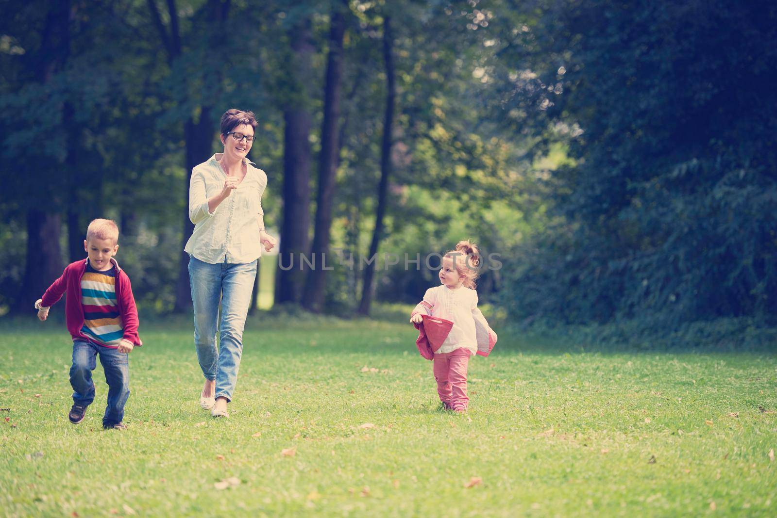 happy family playing together outdoor  in park mother with kids  running on grass