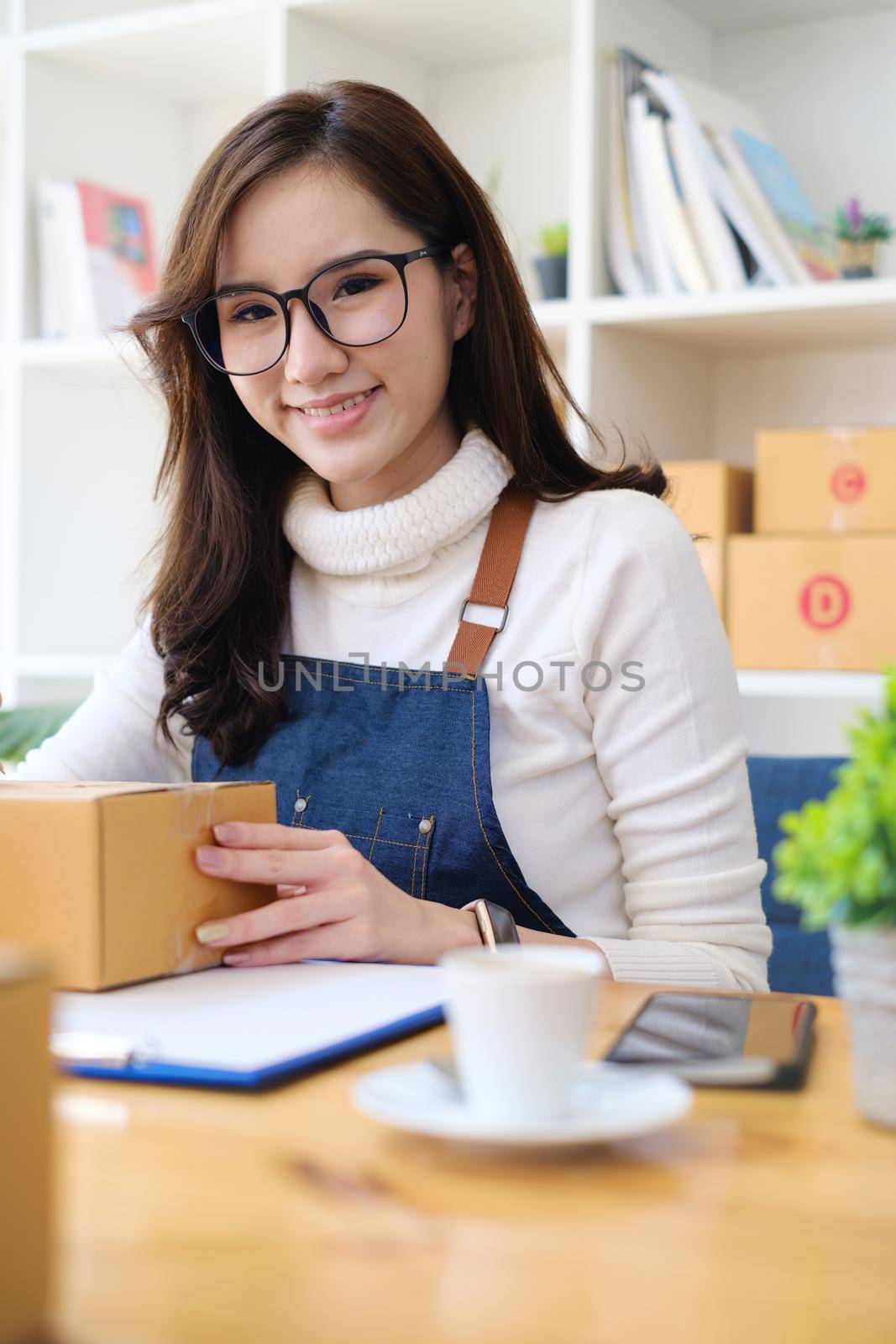 Small business owner with parcel box and working at her home to packing order before send to customer. Freelance working and SME entrepreneur concept. by itchaznong