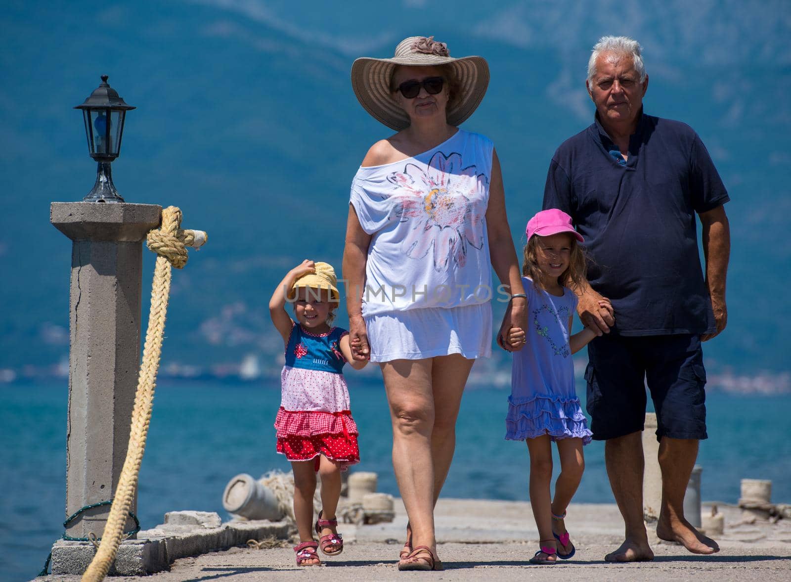 grandparents and granddaughters walking by the sea by dotshock