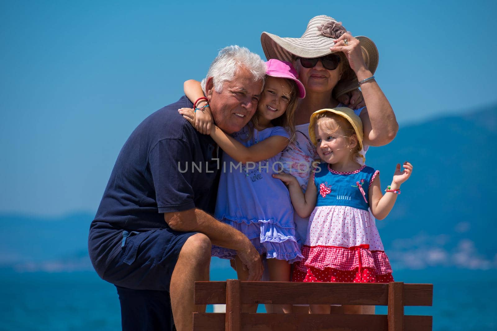 portrait of grandparents and granddaughters by the sea by dotshock
