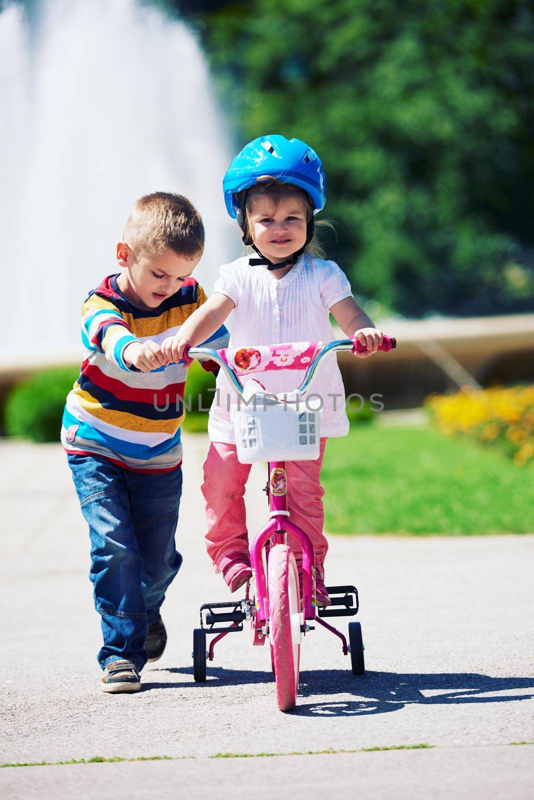 Boy and girl in park learning to ride a bike by dotshock