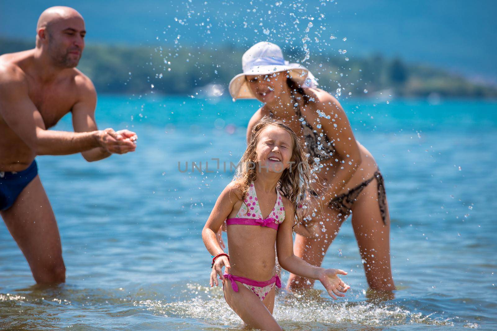 happy family splashing each other at beach by dotshock