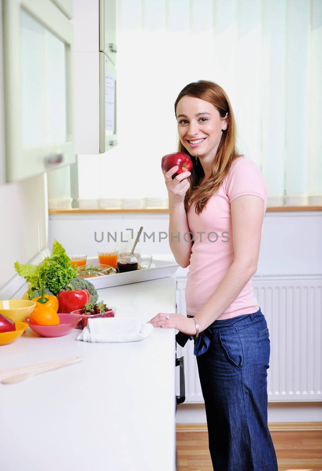 happy young  woman with apple in kitchen by dotshock