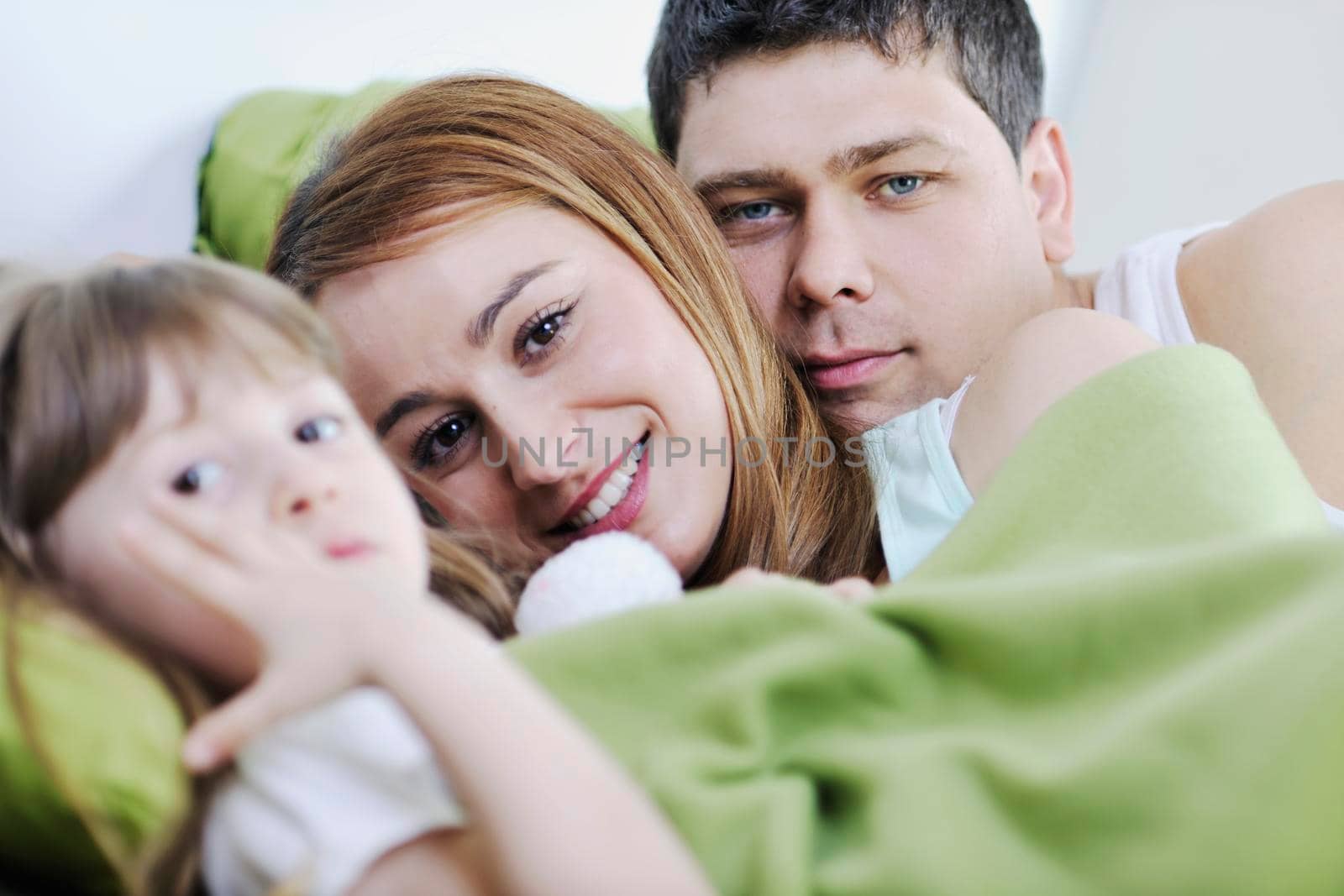 happy young family relaxing in bed 